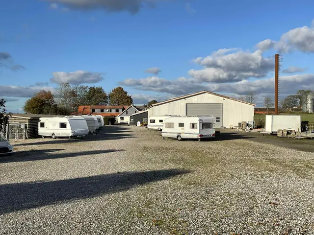 Pladsen med campingvogne på gruset og hallen i baggrunden